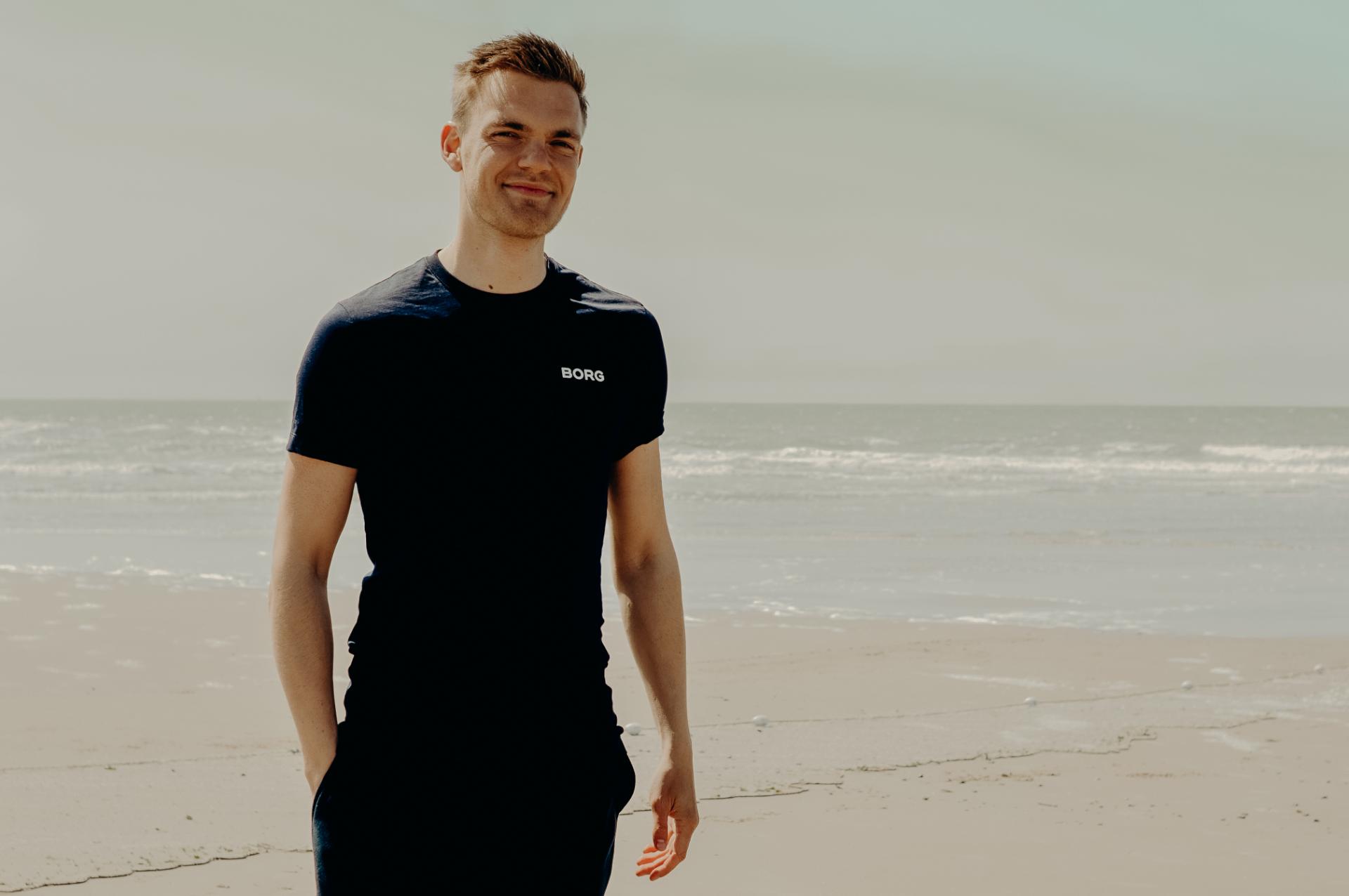 Foto van Nick de Waard die lachend poseert op het strand.