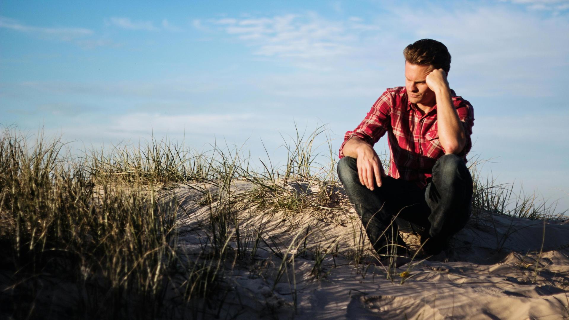 Een man denkt na op het strand over zijn leven. Illustratie bij een verhaal over een angststoornis.